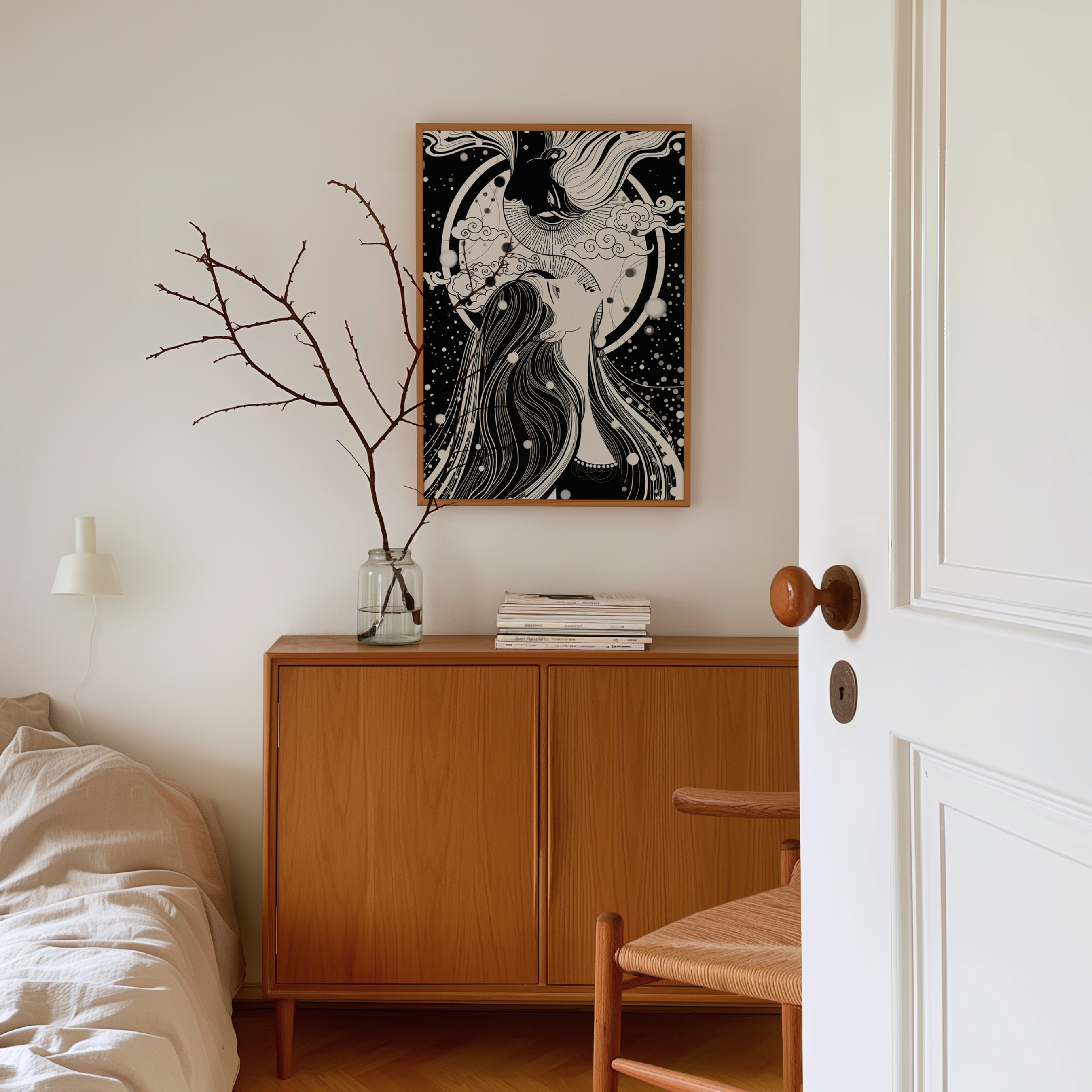 A framed black and white art print featuring an abstract female figure hangs on a white wall above a mid-century modern wooden sideboard in a styled bedroom setting, encouraging self love and self discovery.