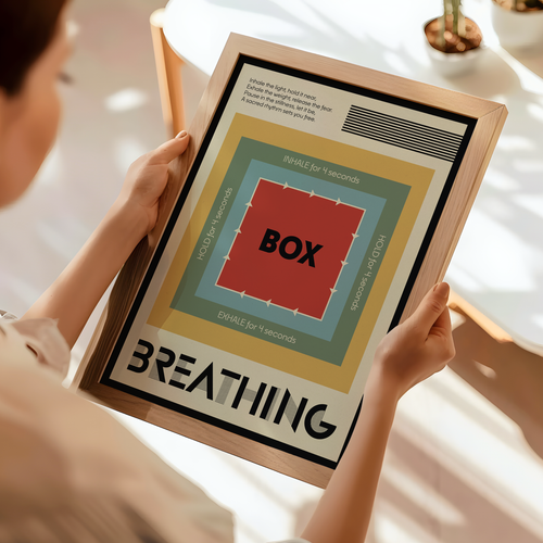 A person holds a framed poster featuring a minimalist breathing exercise graphic with concentric colored squares and the word 'BOXING' in the center, set in a bright, modern room.