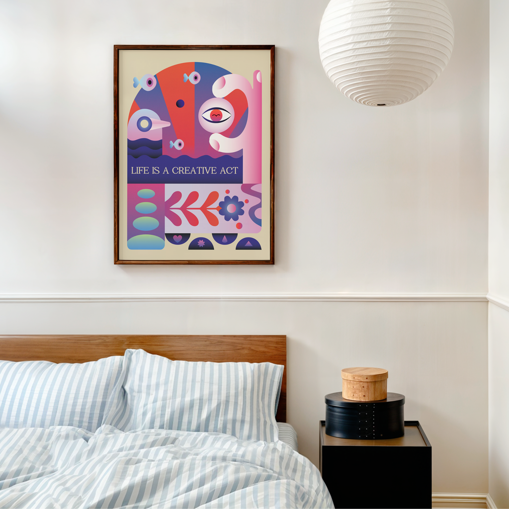 A framed Life Is a Creative Act art print hangs on a bedroom wall above a bed with striped bedding. Inspired by mid century modern and Bauhaus design, the artwork features bold abstract geometric shapes in pink, purple, blue, and red on a cream background with expressive typography. This motivational wall art encourages creativity, curiosity, and self expression, bringing color and inspiration to a modern bedroom, home office, studio, or creative workspace.