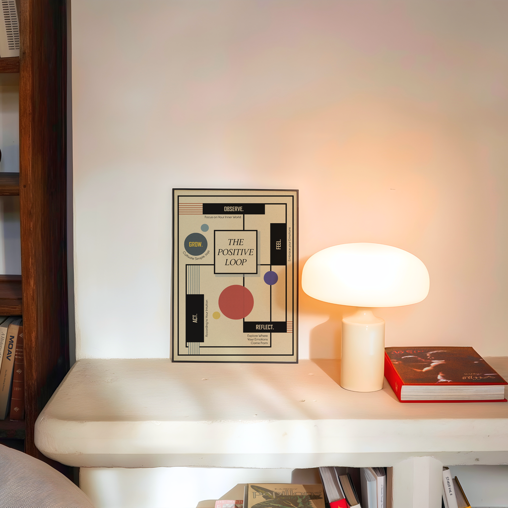 A framed Bauhaus-inspired geometric healing art print titled "The Positive Loop" is displayed on a white shelf beside a glowing mushroom lamp and a book. Contemporary mental health wall art for therapy office decor, counseling offices, psychologist clinics, wellness spaces, and mindful home interiors.