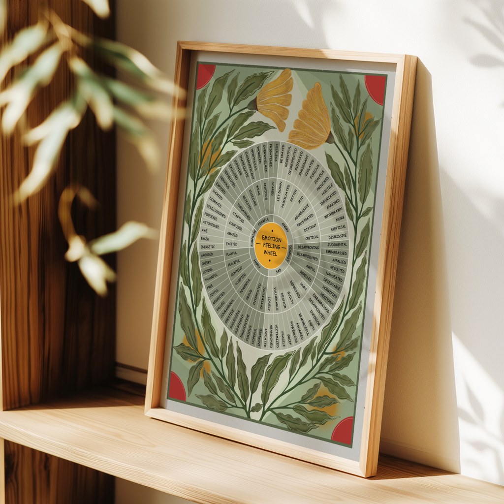 A framed botanical art print with an emotion wheel design and botanical illustrations, leaning on a wooden shelf in a warm, sunlit room.