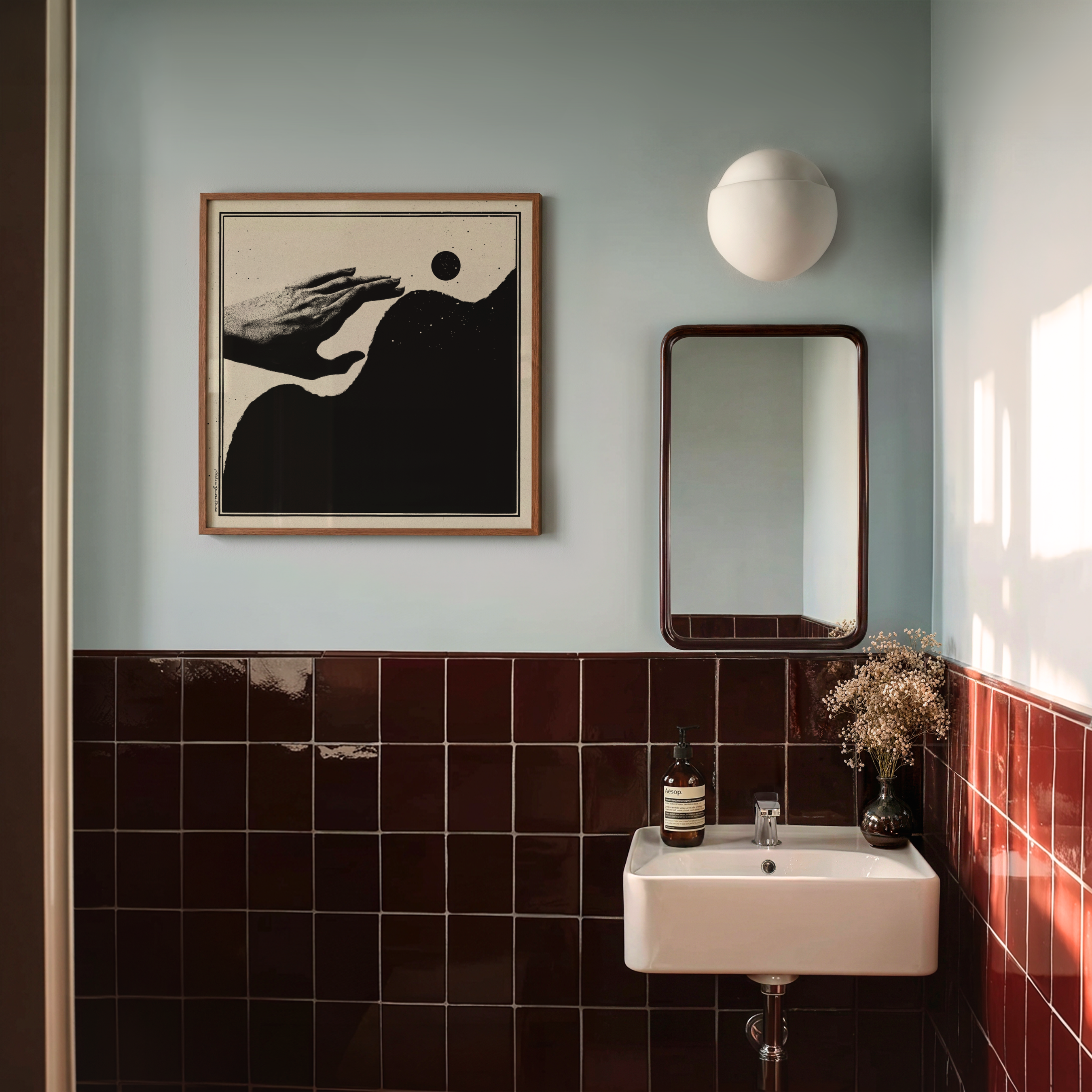A framed Momentum abstract healing art print in black and beige hangs above a white sink in a modern bathroom. Featuring a minimalist hand illustration with organic forms and a black moon, this motivational wall art encourages solace, resilience, hope, and personal growth while complementing Scandinavian, Japandi, and contemporary home decor.